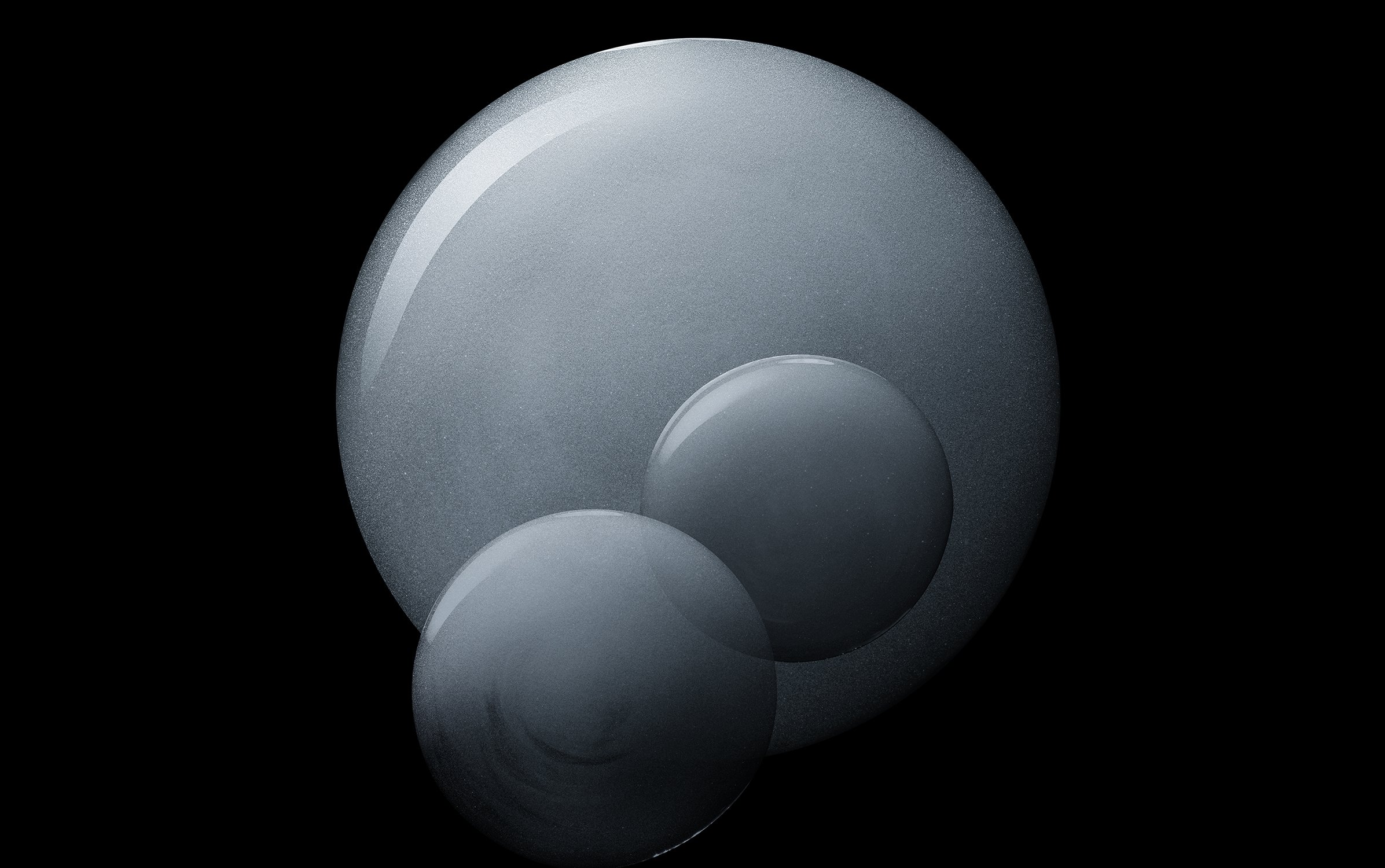 Three spherical shapes of different sizes in a close-up studio composition against a black background with soft, diffused lighting.