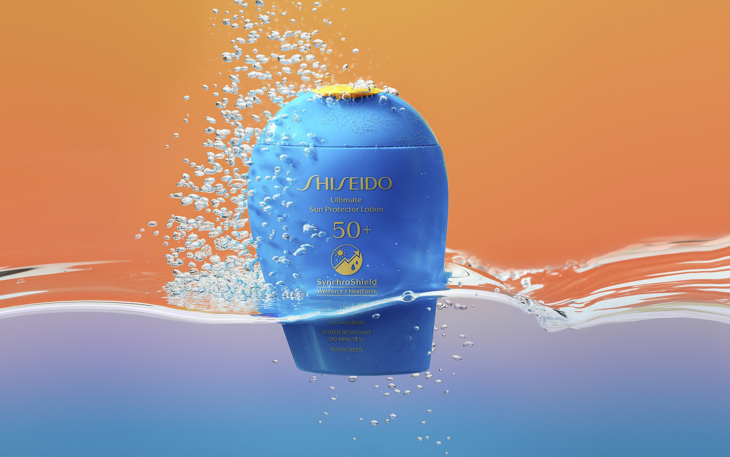 Blue bottle of Shiseido Ultimate Sun Protector Lotion SPF 50+ partially submerged in water, surrounded by bubbles against orange background.