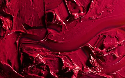 Close-up abstract photograph of thick, glossy red oil paint with visible impasto brushstrokes and rich texture.