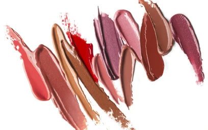 Multiple diagonal smears of various cosmetic shades including reds, pinks, browns, and plums on white background.