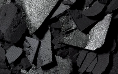 Macro shot of crushed black and silver eyeshadow cakes showing varied matte and shimmering textures.