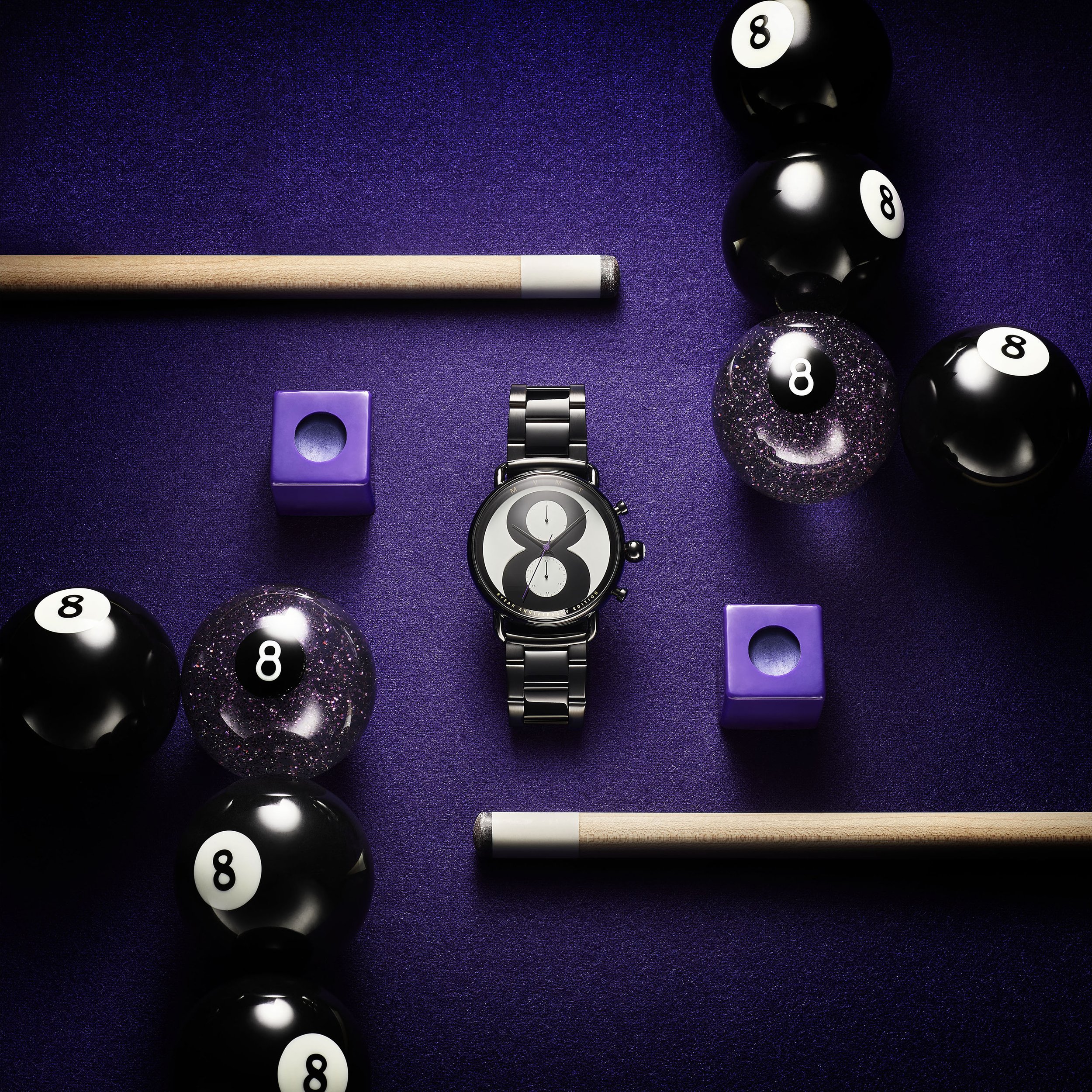 Wristwatch flat lay on purple surface, centered among billiard balls, chalk cubes, and cue sticks, showcasing a lifestyle product.