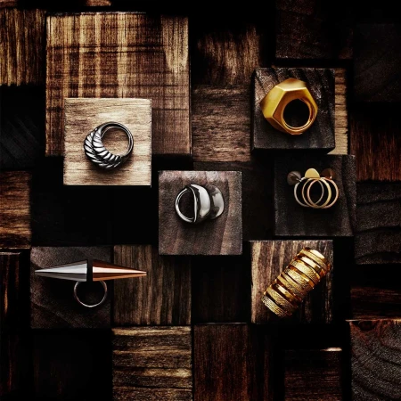 Collection of sculptural gold and silver rings displayed on a geometric arrangement of dark wooden blocks