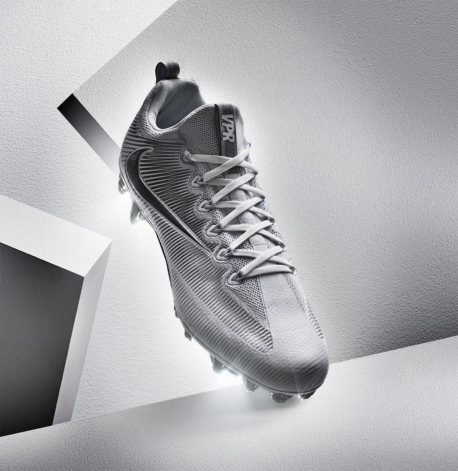 Gray Nike Vapor Edge Shark football cleat on a white geometric surface with studio lighting. Focus on the shoe's design and texture.