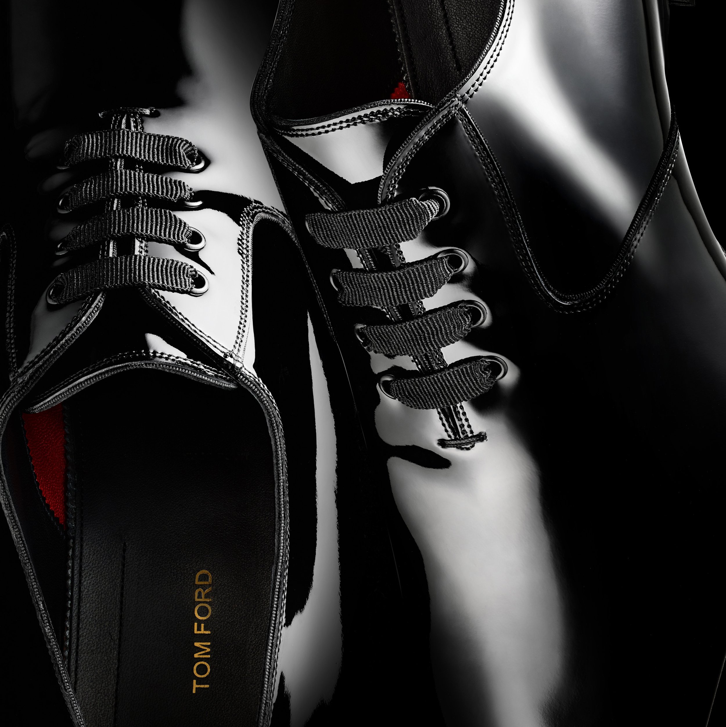 Close-up shot of black patent leather dress shoes with black laces, featuring the Tom Ford logo on the inner sole, sleek and stylish.