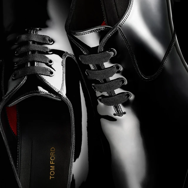 Close-up shot of black patent leather dress shoes with black laces, featuring the Tom Ford logo on the inner sole, sleek and stylish.