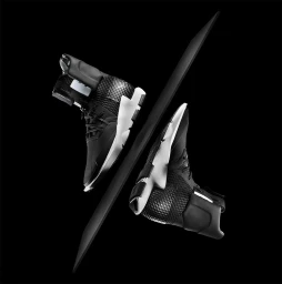High contrast studio product shot of two black high-top sneakers on a black seamless background