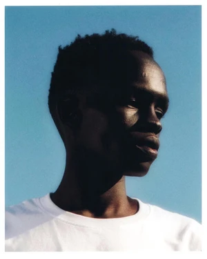 Portrait of a Black man wearing a white t-shirt against a clear blue sky background captured by photographer Bryan Rodner Carr.