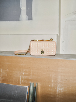 Burberry Lola bag in light pink on a concrete shelf, displayed indoors, showcasing fashion accessory and minimalist design.