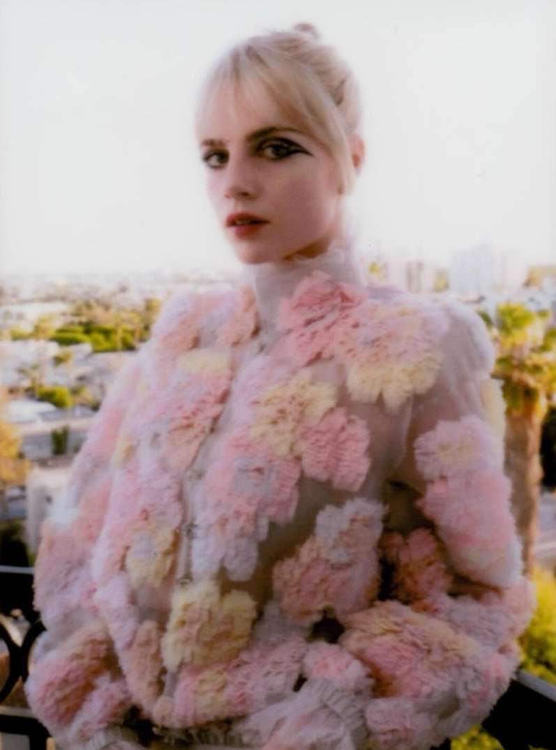 Portrait of a blonde woman in a pastel jacket against an urban background. Fashion-forward look with unique details and styling.