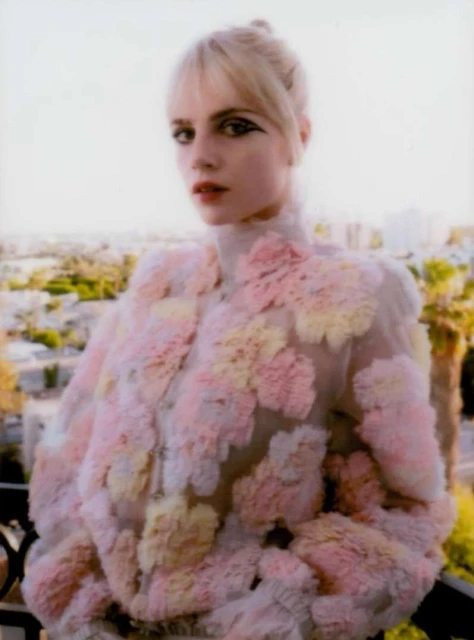 Portrait of a blonde woman in a pastel jacket against an urban background. Fashion-forward look with unique details and styling.