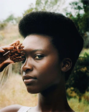Portrait of Black woman holding a pinecone near her face outdoors by Bryan Rodner Carr