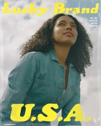 Portrait of a woman with curly hair wearing a denim jumpsuit against a cloudy sky with yellow typography