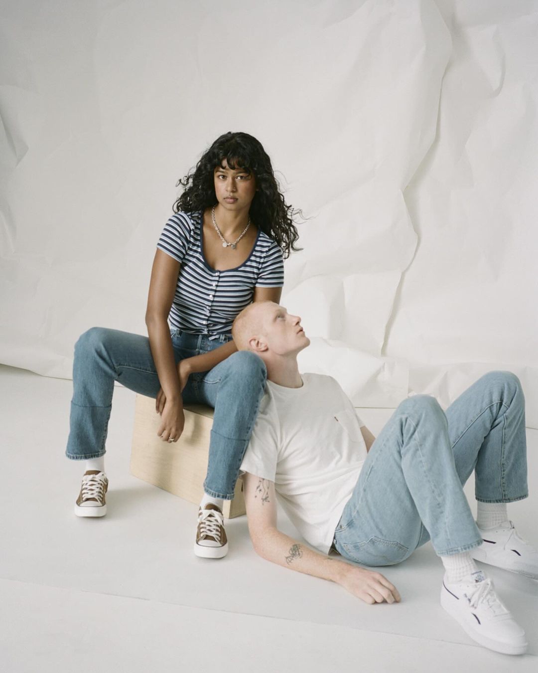 Two models posing in denim against a white studio backdrop, photographed by Levi Walton.