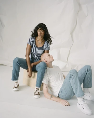 Two models posing in denim against a white studio backdrop, photographed by Levi Walton.