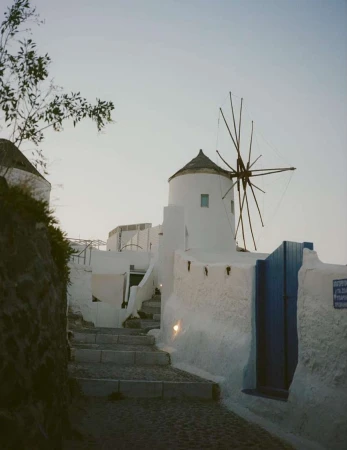 Stone steps lead up to a white windmill in Santorini, Greece, under a soft, early morning sky.  Architectural shot. Peaceful travel destination.