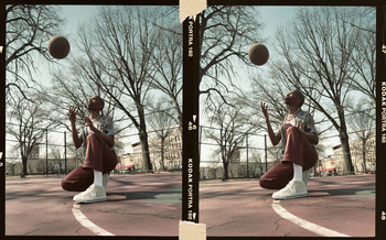 Young adult playing basketball on an outdoor court. Urban setting with overcast lighting and film aesthetic for youthful fashion editorial.