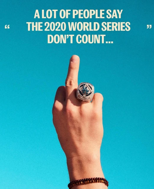 Hand displaying middle finger with 2020 World Series ring set against a clear blue sky; ring symbolizes baseball victory.