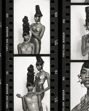 Two Black women with sculpted updos pose in studio with vintage film strip border. Beauty shot with high-fashion hairstyle and neutral makeup.