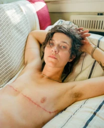 Portrait of a person resting on a striped white sofa with hands behind their head