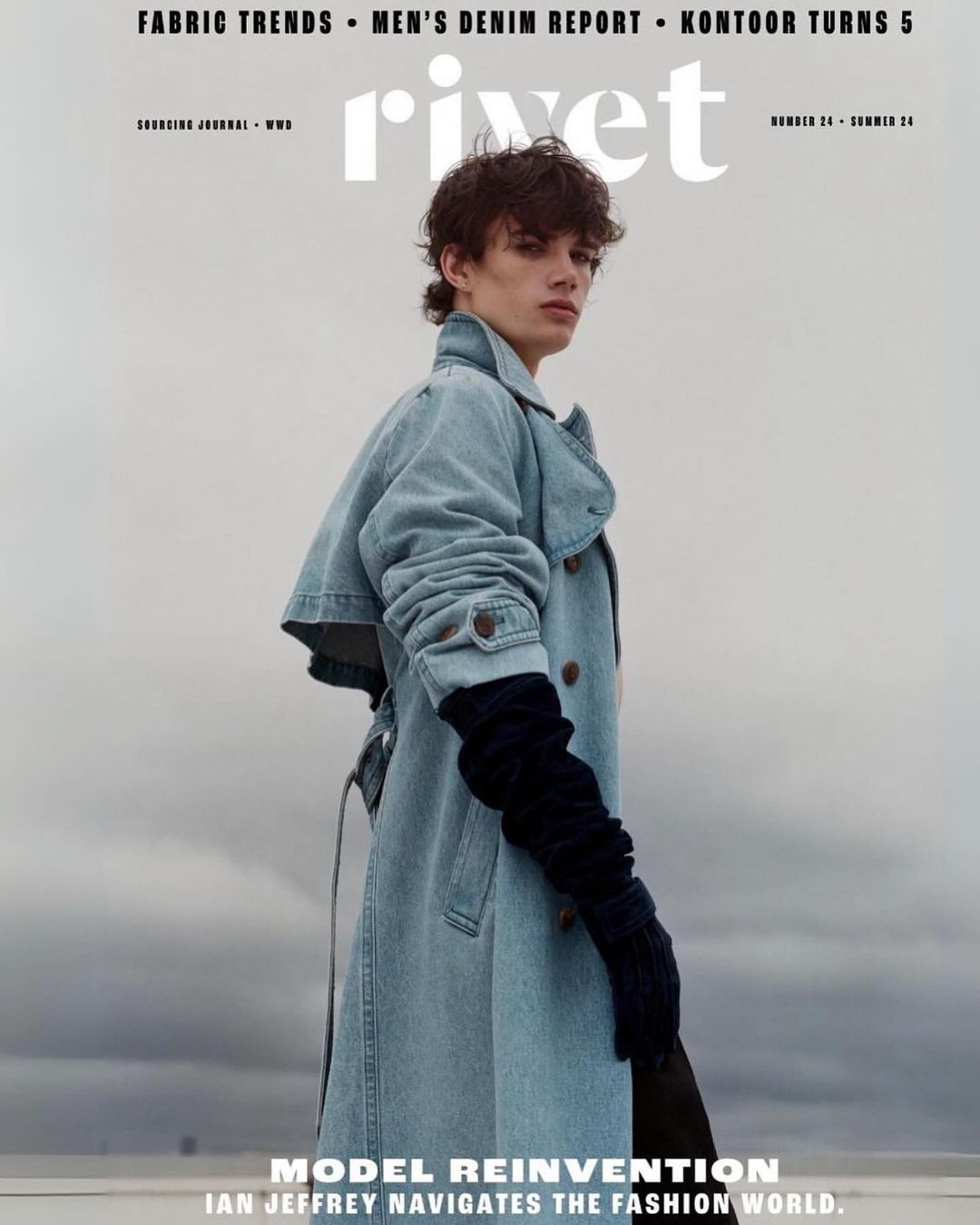 Magazine cover featuring a young adult male model in a denim trench coat and gloves against a cloudy sky, promoting Rivet fashion magazine.