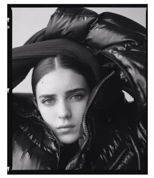 Portrait of a woman wearing a glossy black puffer jacket and dark hat captured by Matthew Priestley