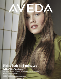 Close-up of a woman with shiny brown hair, wearing a green turtleneck, advertising Aveda shine treatment against a tiled wall.