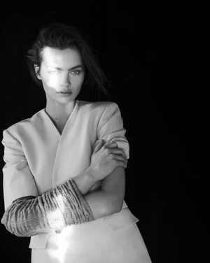 Model with crossed arms wearing a light jacket against a black background by Matthew Priestley