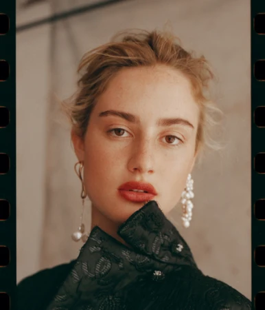 Portrait of a woman wearing statement earrings and a dark patterned jacket by Matthew Priestley