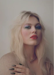 Portrait of a blonde woman with colorful eyeshadow, red lipstick, and long dark nails by Matthew Priestley