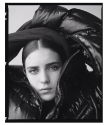 Portrait of a woman wearing a glossy black puffer jacket and dark hat captured by Matthew Priestley