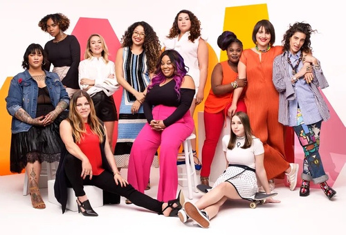 Group portrait of ten diverse women posing together against a bright white background with colorful geometric shapes