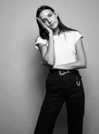 Portrait of a woman wearing a white t-shirt and dark trousers against a grey seamless background