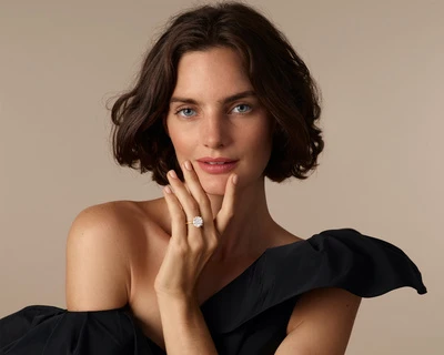 Close-up portrait of a woman with short dark hair wearing a black one-shoulder top and diamond ring, photographed by Nadya Wasylko.