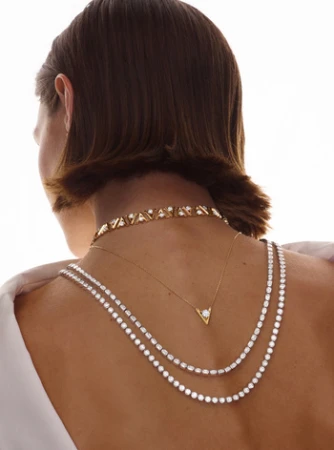 Close-up back view of a woman wearing layered diamond tennis necklaces and a gold choker necklace by photographer Nadya Wasylko