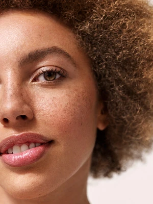 Close-up portrait of a woman with freckles and curly brown hair by photographer Nadya Wasylko