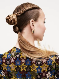 Profile view of a woman with an intricate braided hairstyle and star-patterned top against a white background