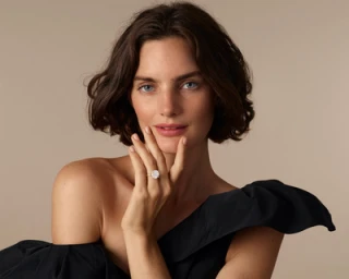 Close-up portrait of a woman with short dark hair wearing a black one-shoulder top and diamond ring, photographed by Nadya Wasylko.