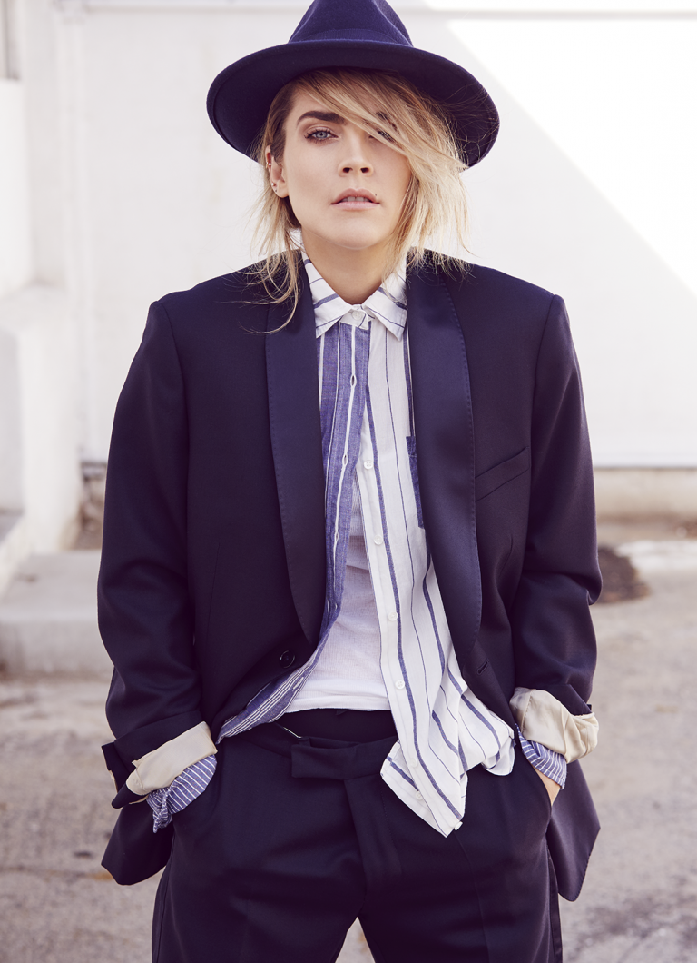Portrait of a blonde woman wearing a fedora hat, striped button-down shirt, and a dark blazer by James Dimmock in Los Angeles.