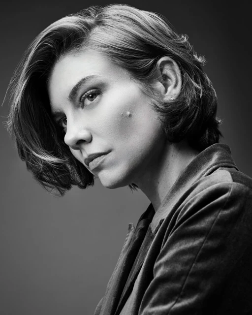 Black and white portrait of a woman with short hair wearing a dark jacket, gazing off to the side in a studio setting.