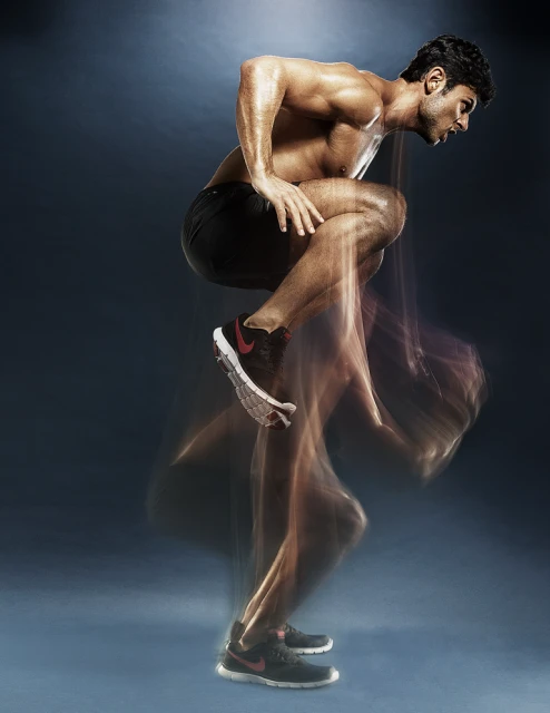 An athletic, shirtless man is mid-motion during a workout with a blue gradient background. The motion blur creates a sense of dynamism.