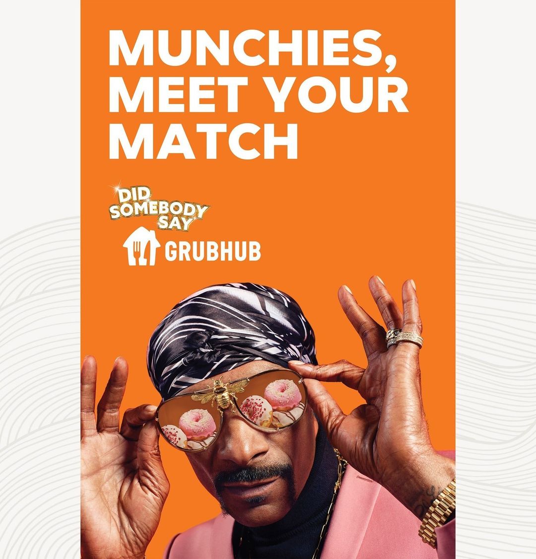 Snoop Dogg wears novelty donut glasses and a headscarf in a Grubhub advertisement with an orange backdrop and the Grubhub logo.