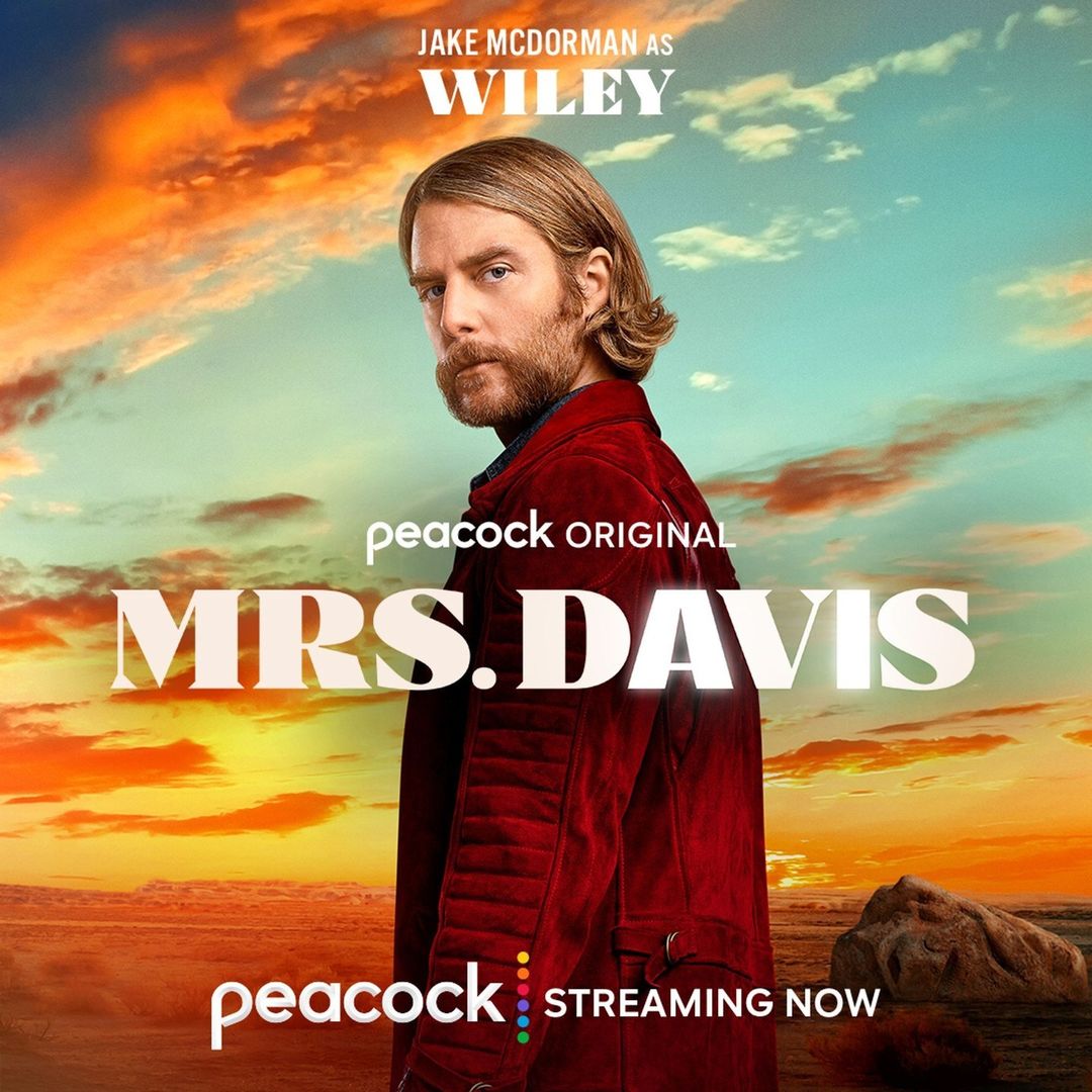 Promotional image of Jake McDorman as Wiley in Peacock Original series, Mrs. Davis, against a sunset sky and ocean.