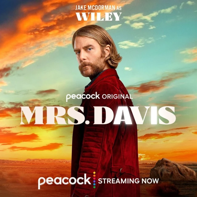 Promotional image of Jake McDorman as Wiley in Peacock Original series, Mrs. Davis, against a sunset sky and ocean.
