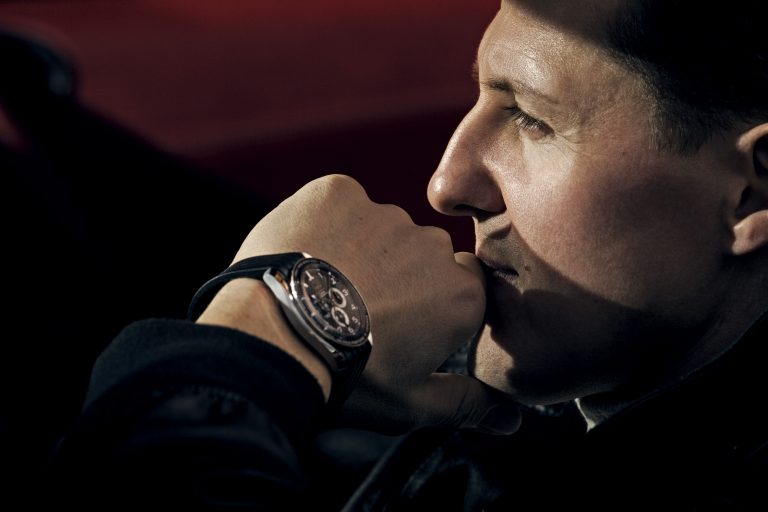Close-up profile portrait of a man resting his chin on his fist, wearing a chronograph watch by photographer James Dimmock.