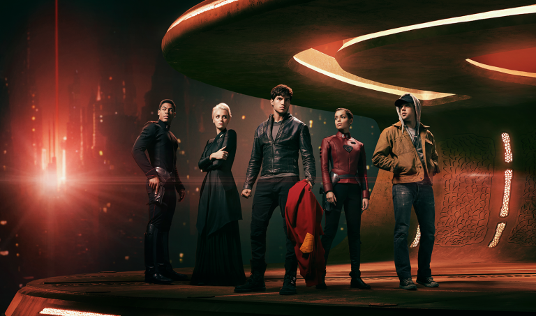 Group of five young adult actors in futuristic costumes standing on a circular platform with a cityscape and abstract lighting in the background.