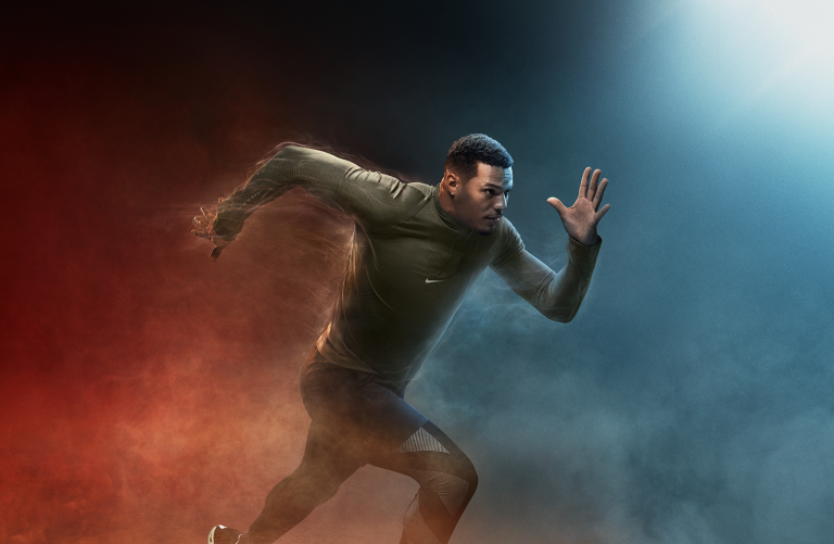Athletic man in running pose with arm raised and dark activewear against a two-tone red and blue background with motion effects.