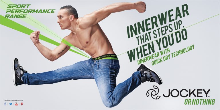 Athletic man in motion wearing jeans and Jockey underwear for a sportswear campaign on a white background with green accents and text.