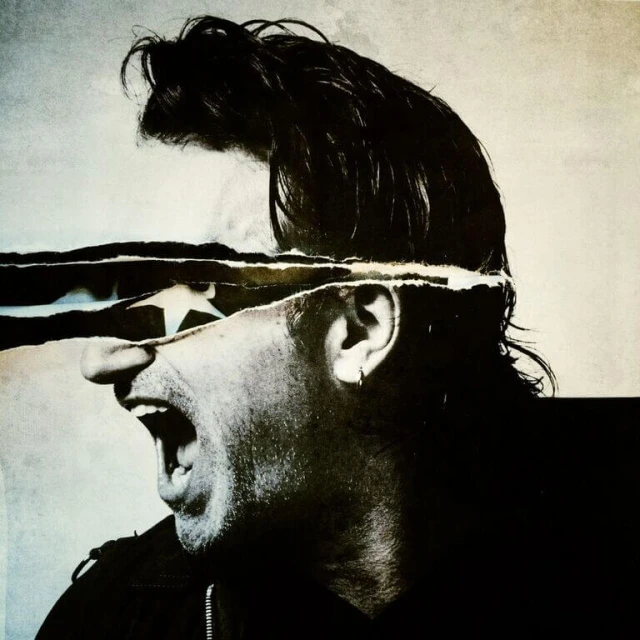 Artistic portrait of a man with his mouth open in a scream, face partially obscured by a torn paper effect, and dark moody lighting.
