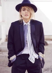 Portrait of a blonde woman wearing a fedora hat, striped button-down shirt, and a dark blazer by James Dimmock in Los Angeles.